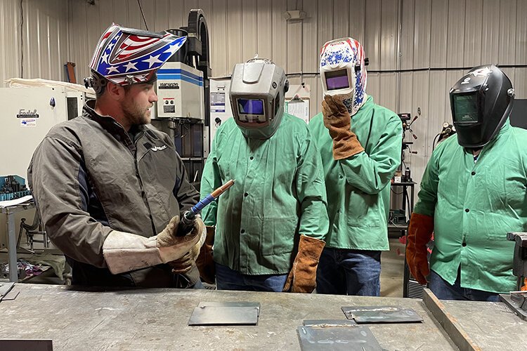 A worker at Blue Water Controls exhibits a welding tutorial for Yale High School students during Manufacturing Day.