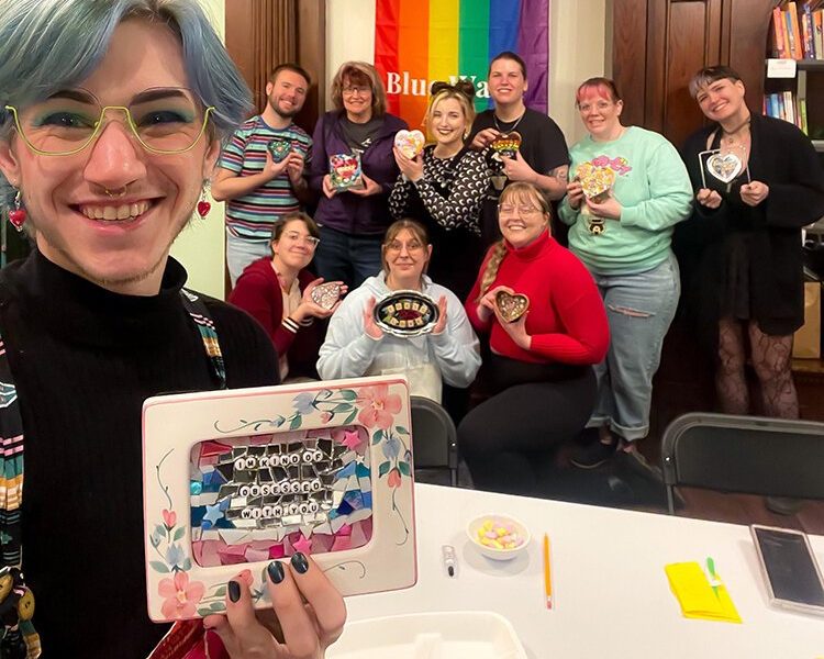 Ren Sontsmann takes a picture with their mosaic class showing off their creations.