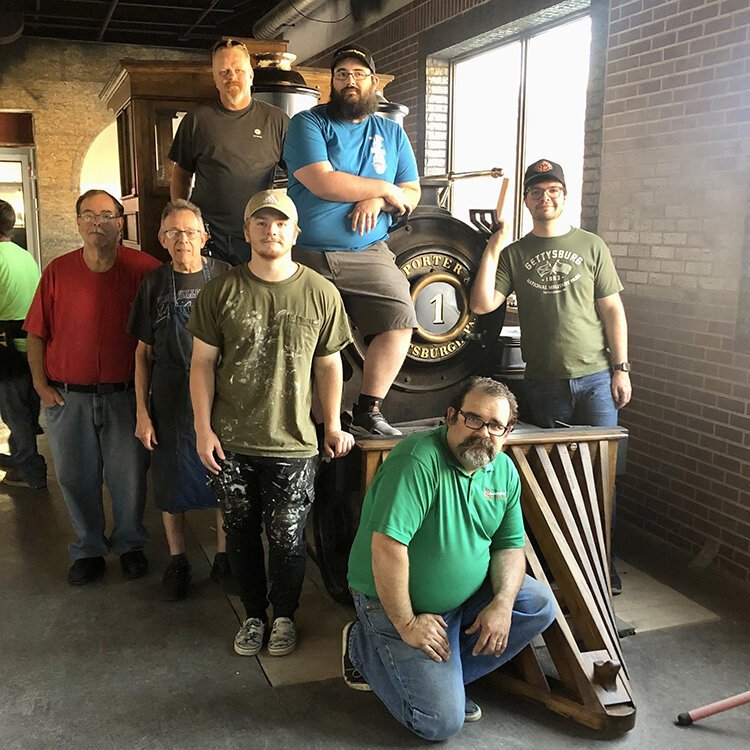 A team who worked on restoring the D.B. Harrington pose for a photo with the locomotive.
