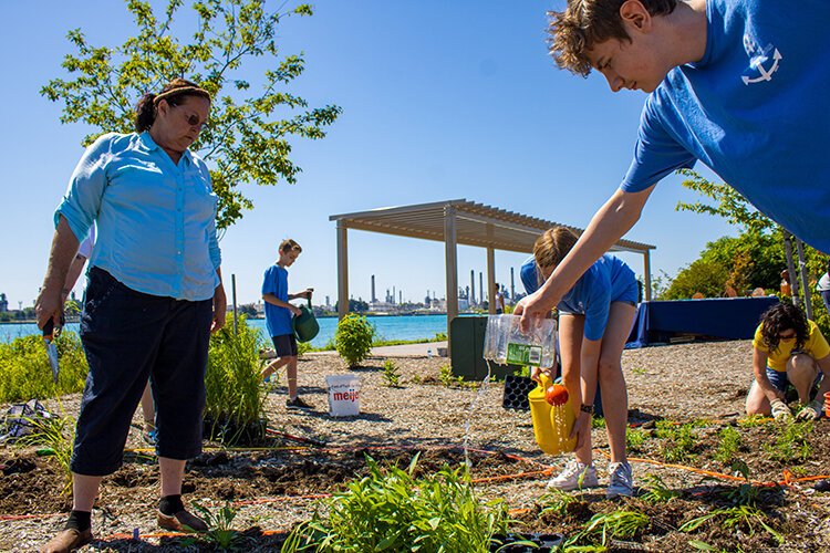 Volunteers plant and water the new plants at the Blue Water River Walk in Port Huron.