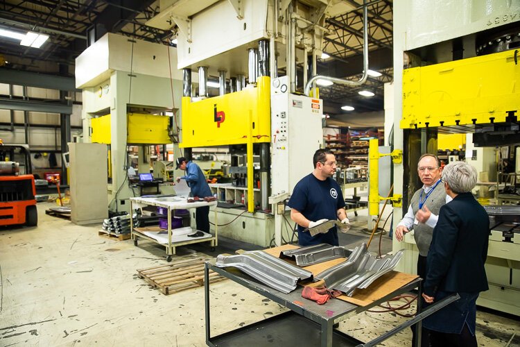 PTM Human Resources Director John Tucker (center) and Ann Austin of Michigan Works (right) chat with employees.