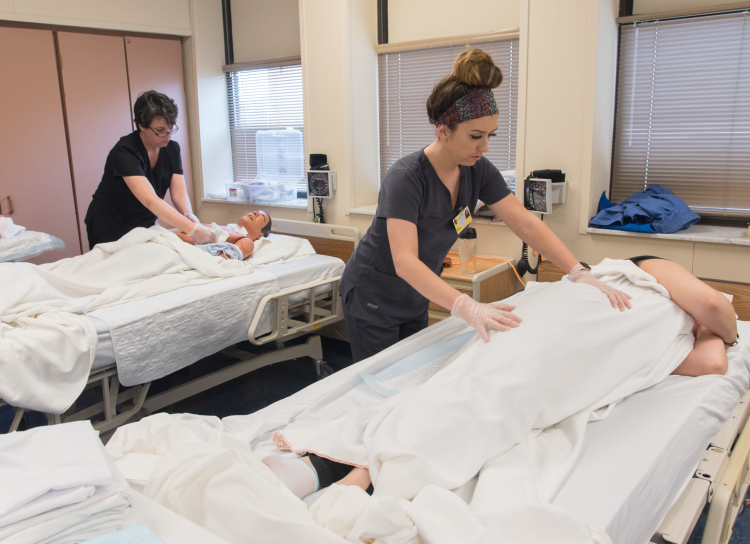 Students practice their skills during a lab for their CNA course.