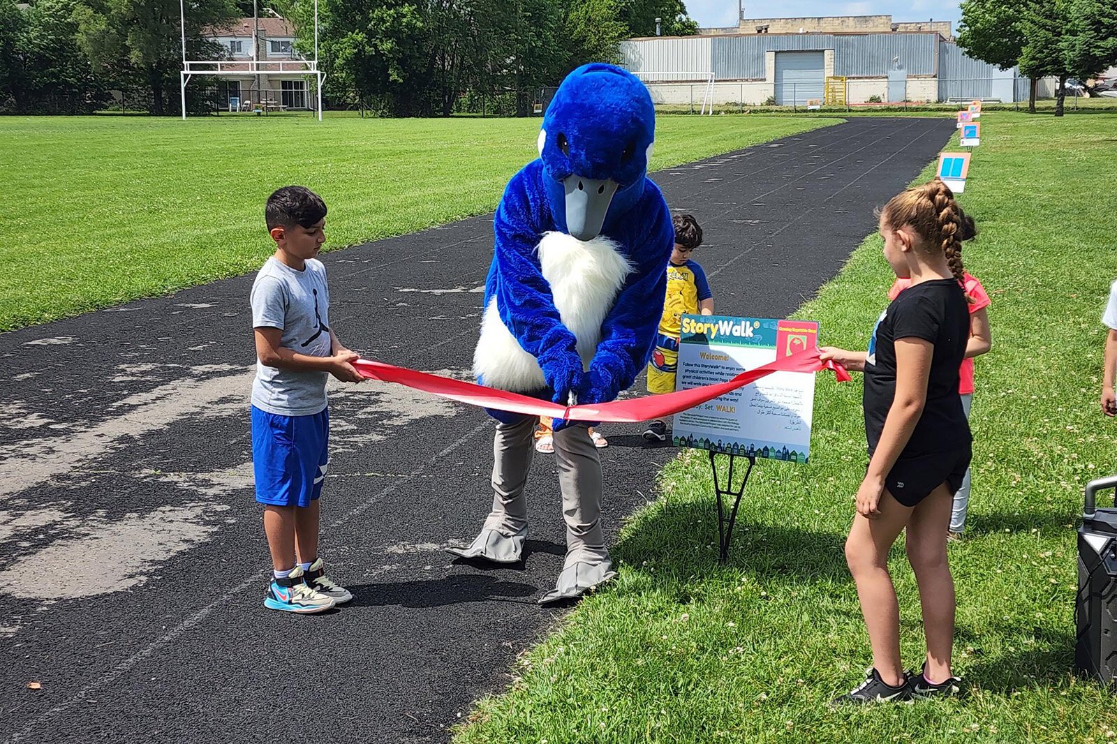 The ribbon cutting for a StoryWalk® exhibit organized by Leaders Advancing and Helping Communities and other partners.