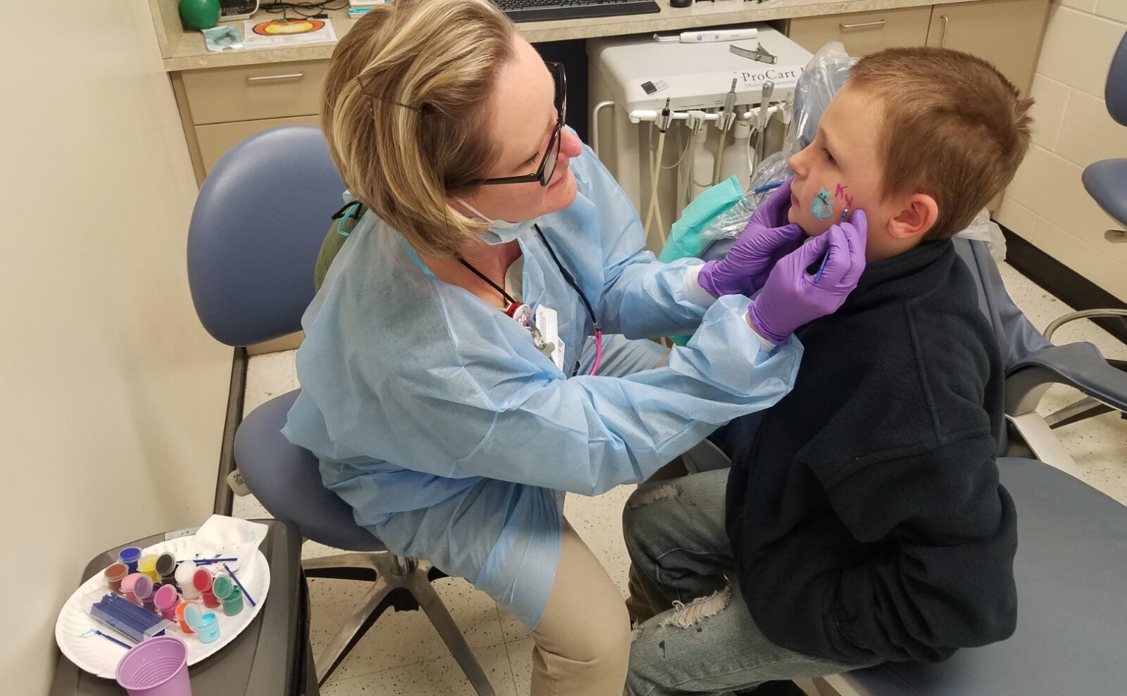 After receiving dental care at the Delta Dental Center at Oyler, a student gets his face painted while waiting for the bus back to school.