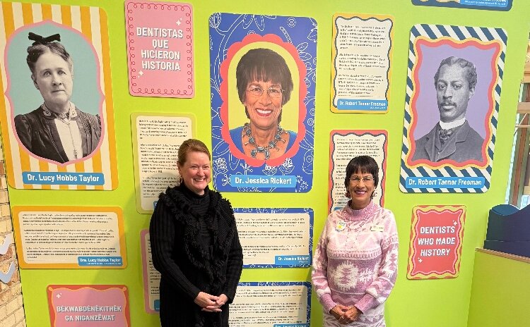 Dr. Jessica Rickert, DDS, and Grand Rapids Public Museum CEO Maggie Lancaster. Behind them, the exhibit highlights the USA's first female, American Indian, and African American dentists