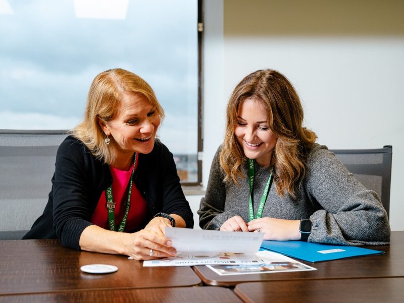 Laurie Arora, PACE Southeast Michigan vice president of public affairs, philanthropy, and organizational development; and Sadie Shattuck, PACE Southeast Michigan's grant and communications specialist, look over health literacy handouts.