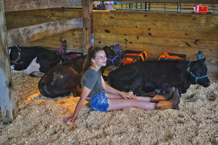 A girl relaxes with her cow.